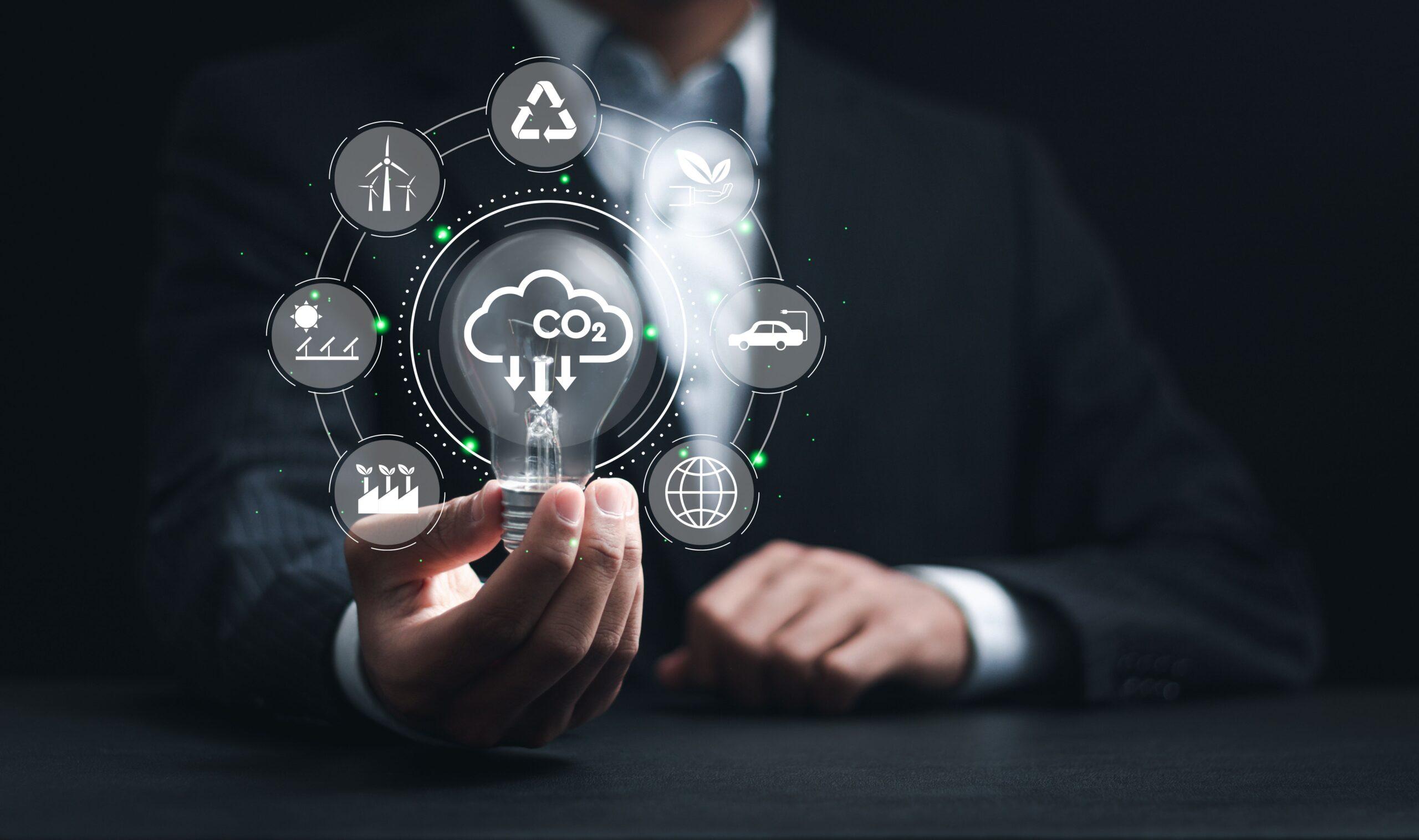 Geschäftsmann hält Glühbirne mit CO2-reduzierenden Symbolen für den Klimawandel, um die globale Erwärmung und nachhaltige Entwicklung sowie ein grünes Geschäftskonzept zu begrenzen.